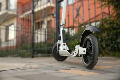 Photo of Modern electric kick scooter on city street, closeup