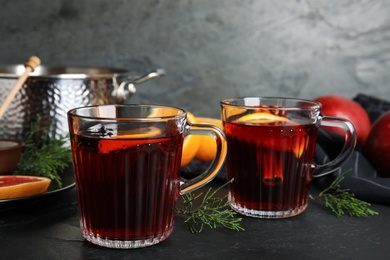 Photo of Tasty mulled wine and fresh ingredients on black table