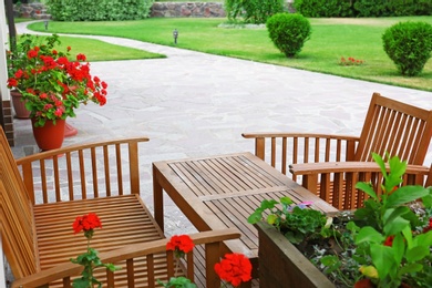 Photo of Modern wooden furniture near backyard with beautiful garden