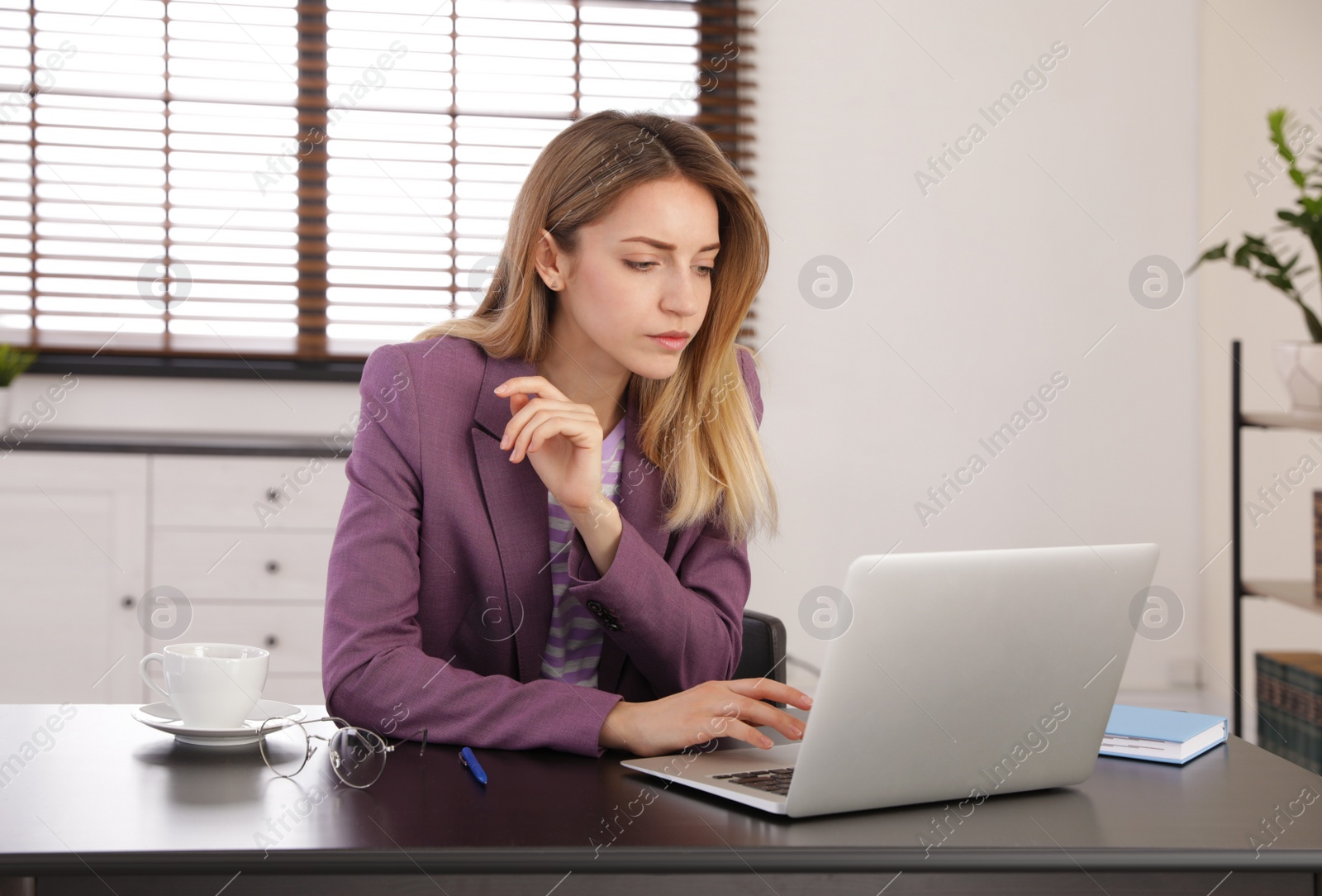 Image of Young woman working on laptop in office