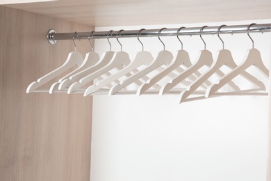 Photo of Clothes rail with wooden hangers in wardrobe