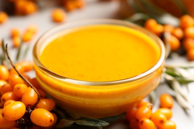 Photo of Delicious sea buckthorn jam and fresh berries on table, closeup