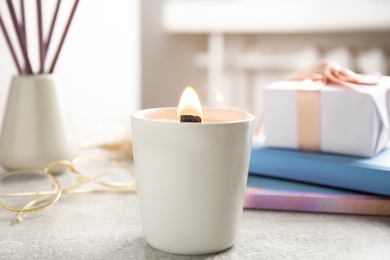 Photo of Burning candle with wooden wick on grey table