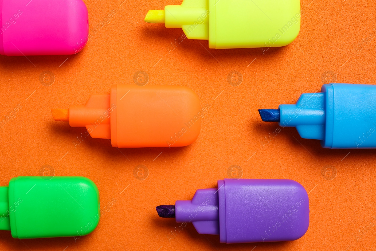 Photo of Set of highlighters on orange background, flat lay