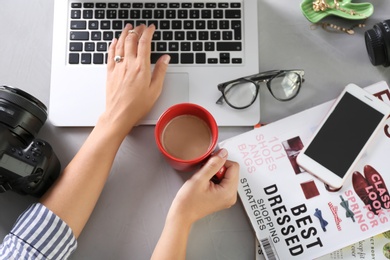 Female blogger using laptop at table, top view