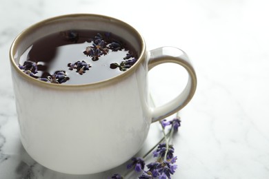 Fresh delicious tea with lavender and beautiful flowers on white marble table, closeup