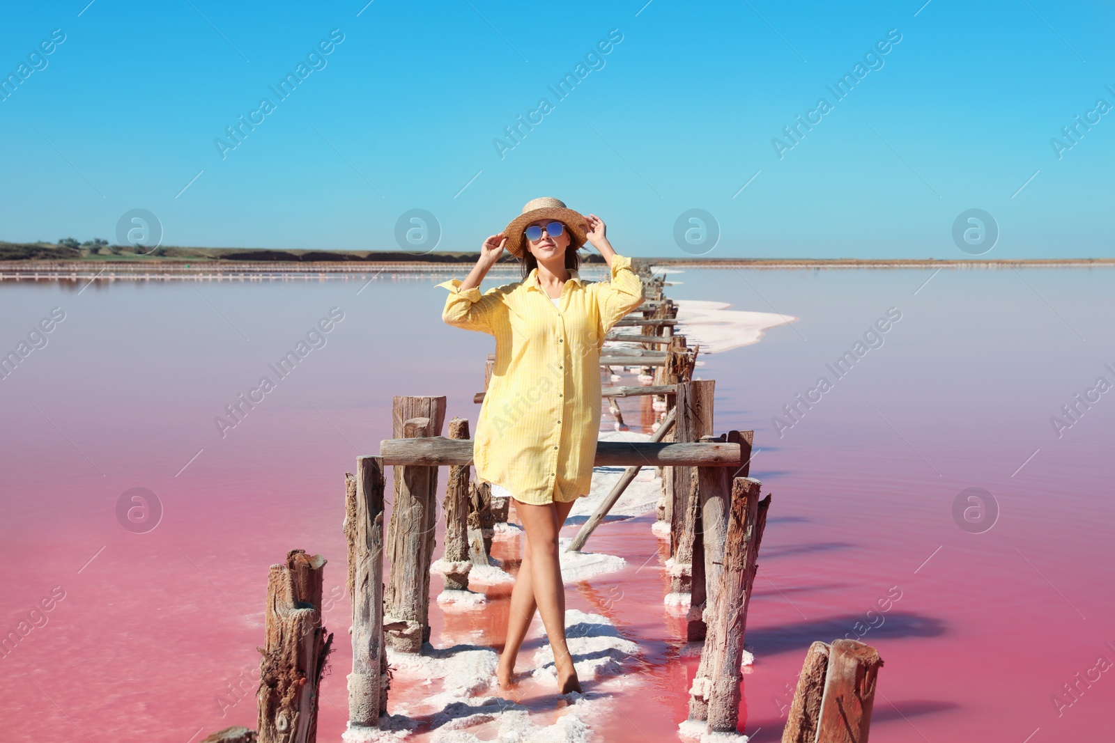 Photo of Beautiful woman with hat posing near pink lake on summer day