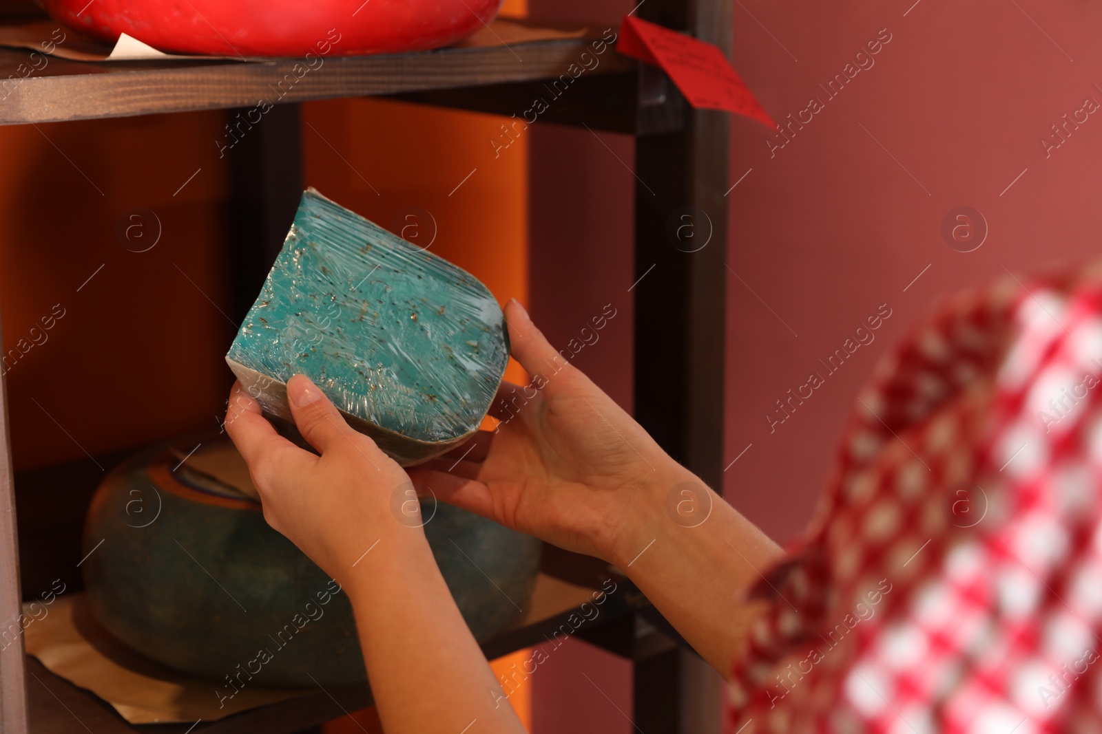 Photo of Woman choosing tasty cheese from display in store