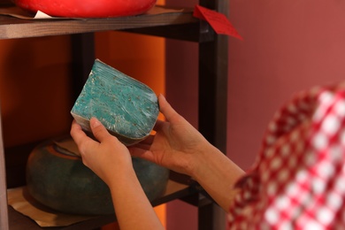 Photo of Woman choosing tasty cheese from display in store