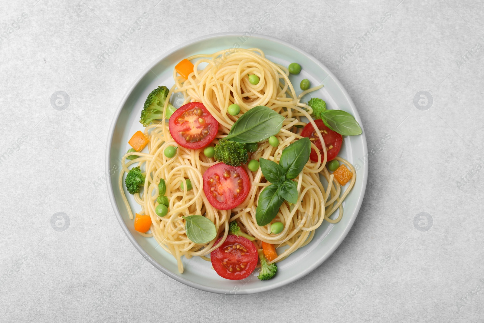Photo of Plate of delicious pasta primavera on light gray table, top view