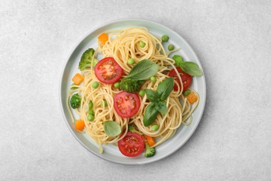 Plate of delicious pasta primavera on light gray table, top view