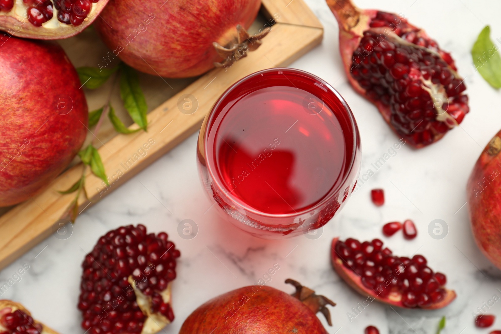 Photo of Tasty pomegranate juice in glass and fresh fruits on white marble table, flat lay
