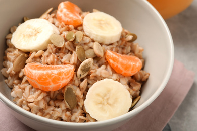 Tasty oatmeal with fruits and pumpkin seeds on table, closeup. Healthy breakfast