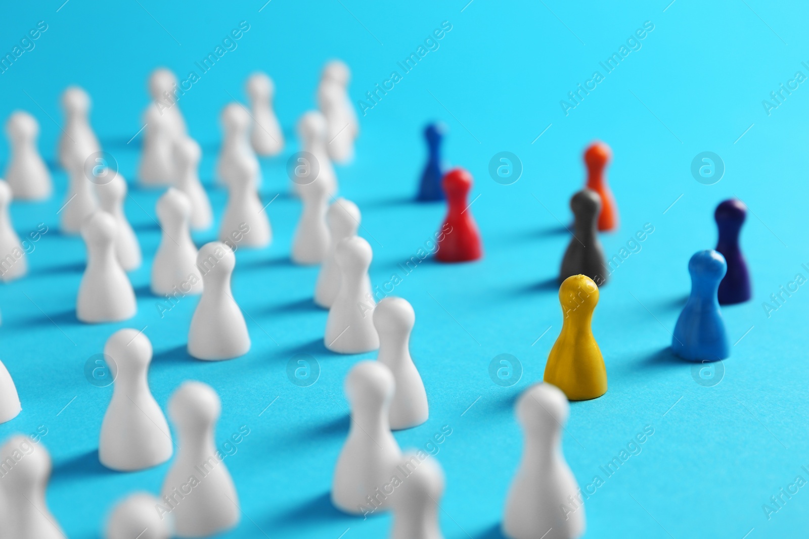 Photo of Colorful pawns on light blue background. Social inclusion concept