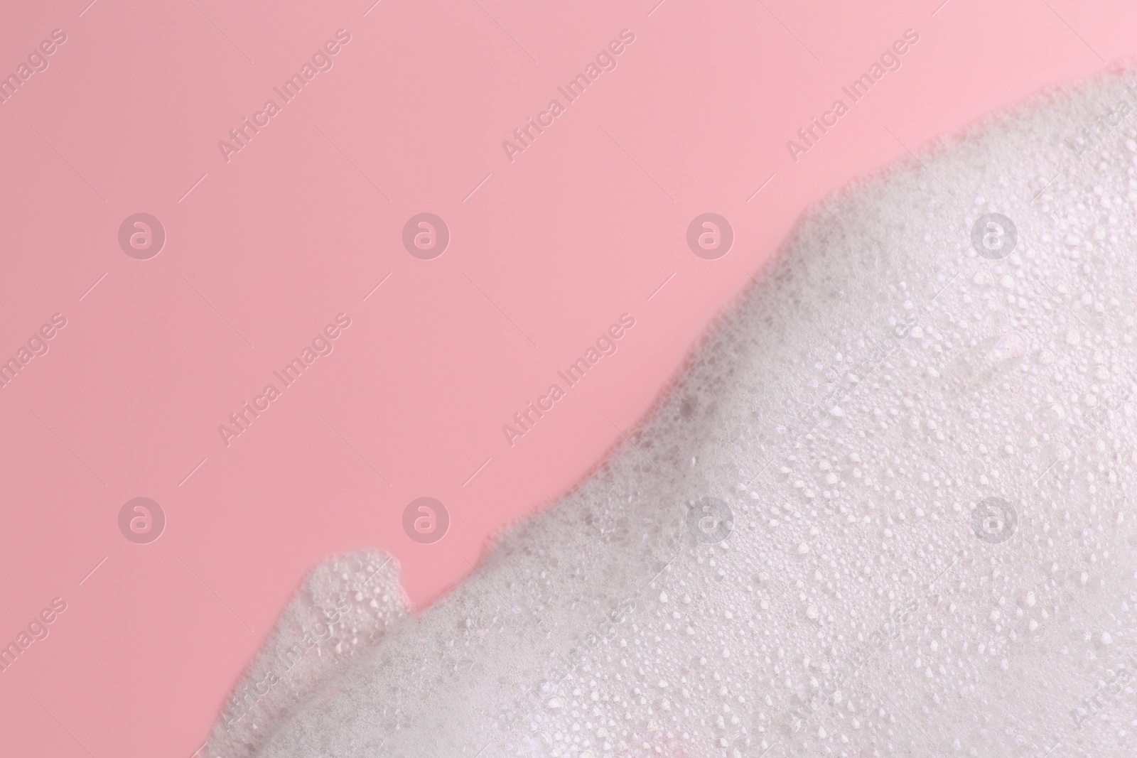 Photo of White fluffy foam on pink background, top view. Space for text