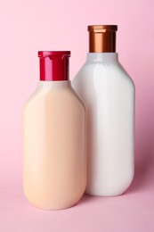 Photo of Bottles of shampoo on pale pink background