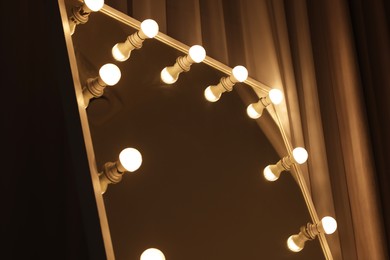 Photo of Beautiful mirror with light bulbs in makeup room, closeup