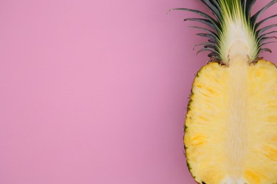 Photo of Half of ripe pineapple on pink background, top view. Space for text