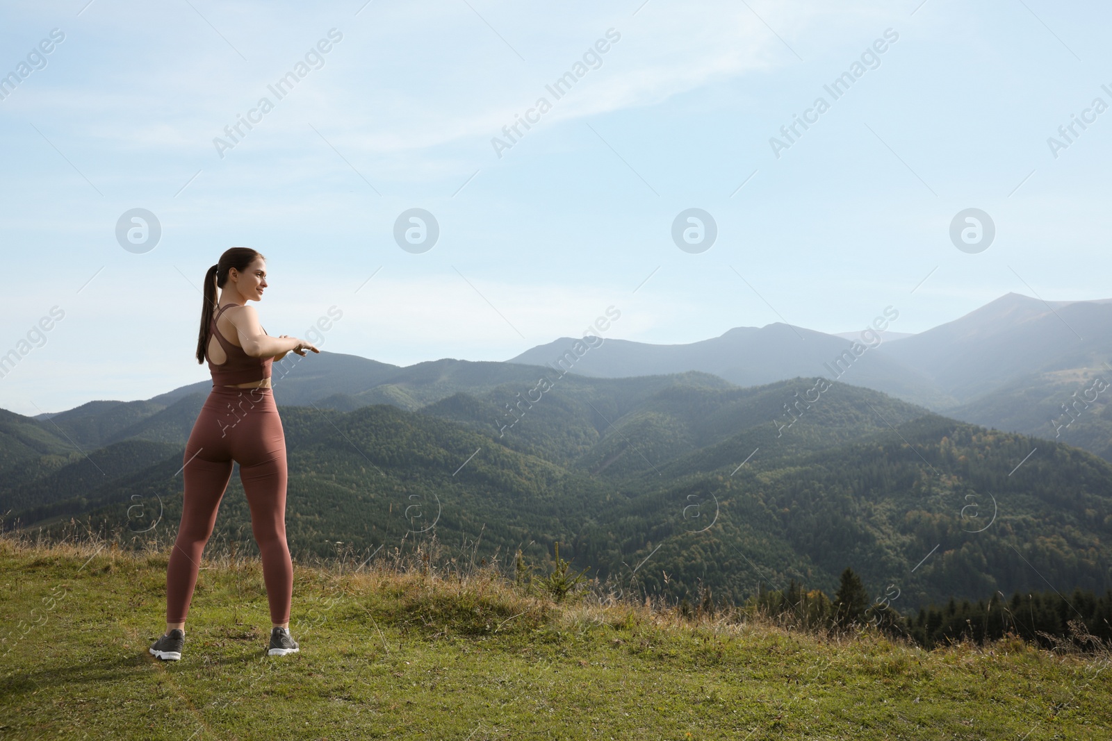 Photo of Young woman doing morning exercise in mountains, space for text