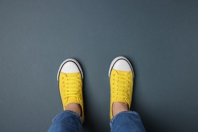 Woman in stylish gumshoes on grey background, top view