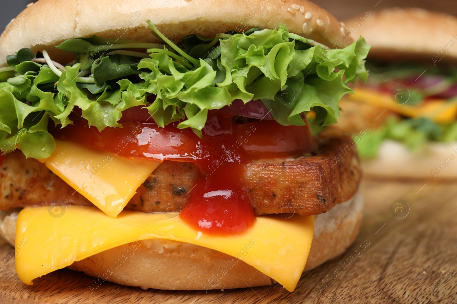 Photo of Delicious burger with tofu, fresh vegetables and sauce on wooden table, closeup