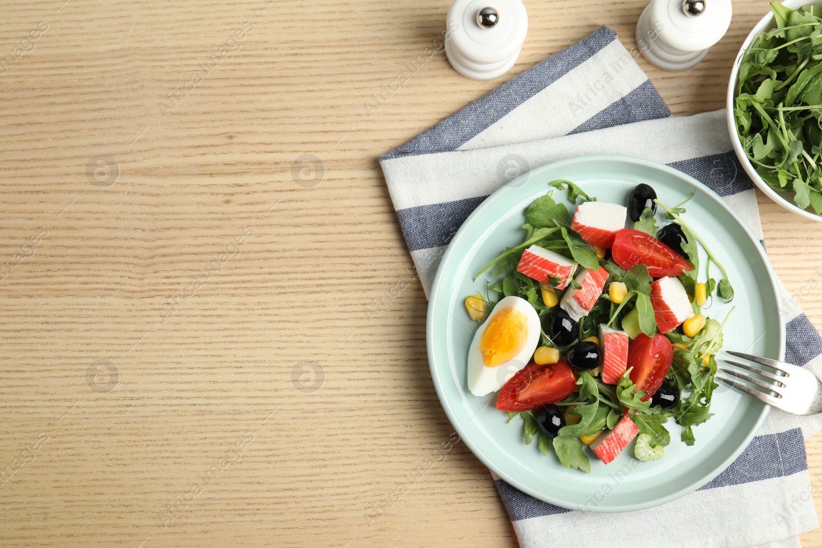 Photo of Tasty crab stick salad served on wooden table, flat lay. Space for text