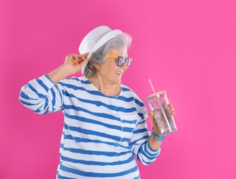 Photo of Portrait of cool grandmother with drink on color background, space for text