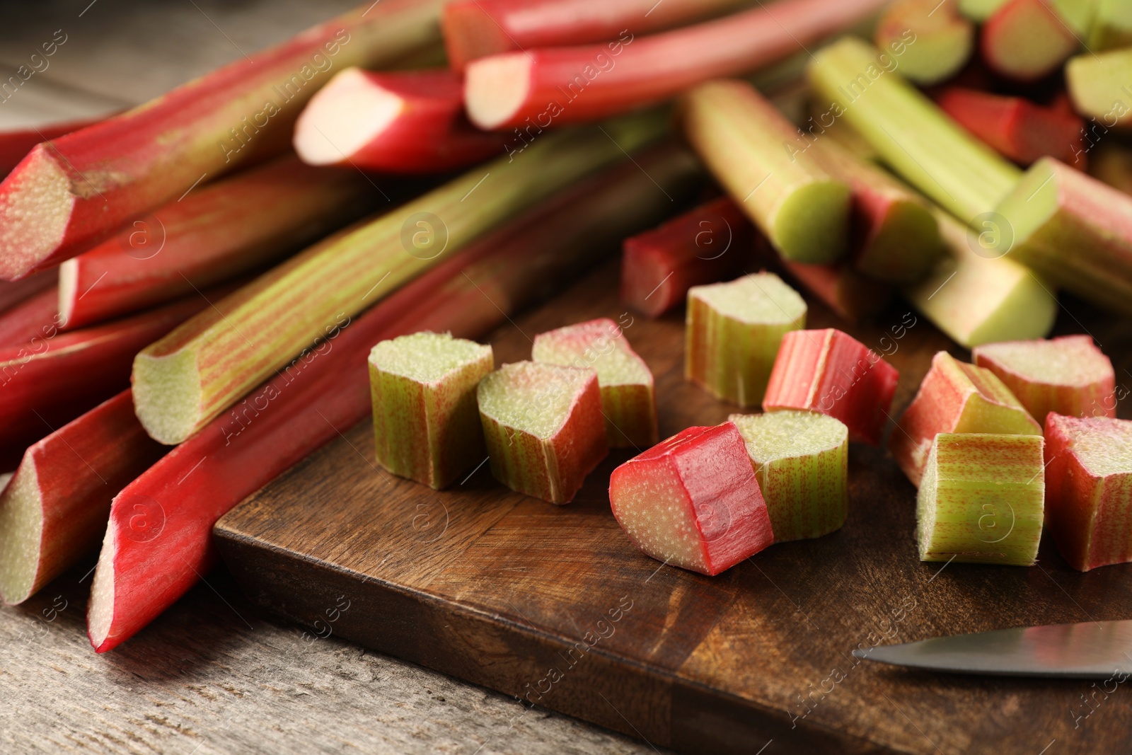 Photo of Many cut rhubarb stalks on wooden table, closeup