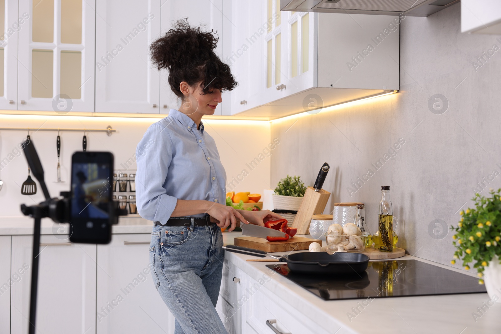 Photo of Food blogger cooking while recording video in kitchen