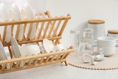 Drying rack with clean dishes on light marble countertop in kitchen