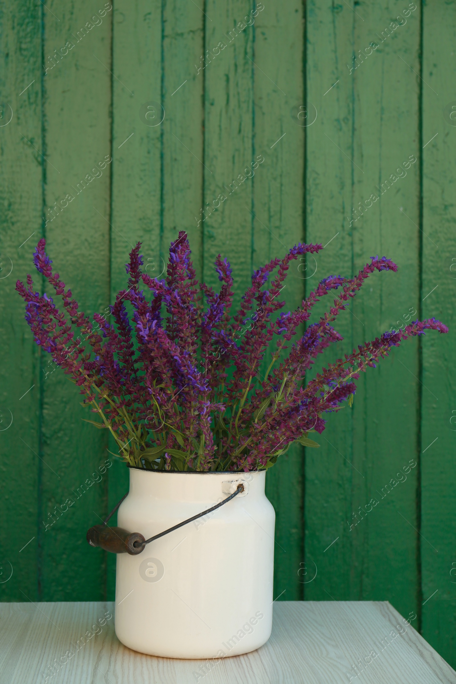 Photo of Beautiful bouquet with field flowers in can on white wooden table