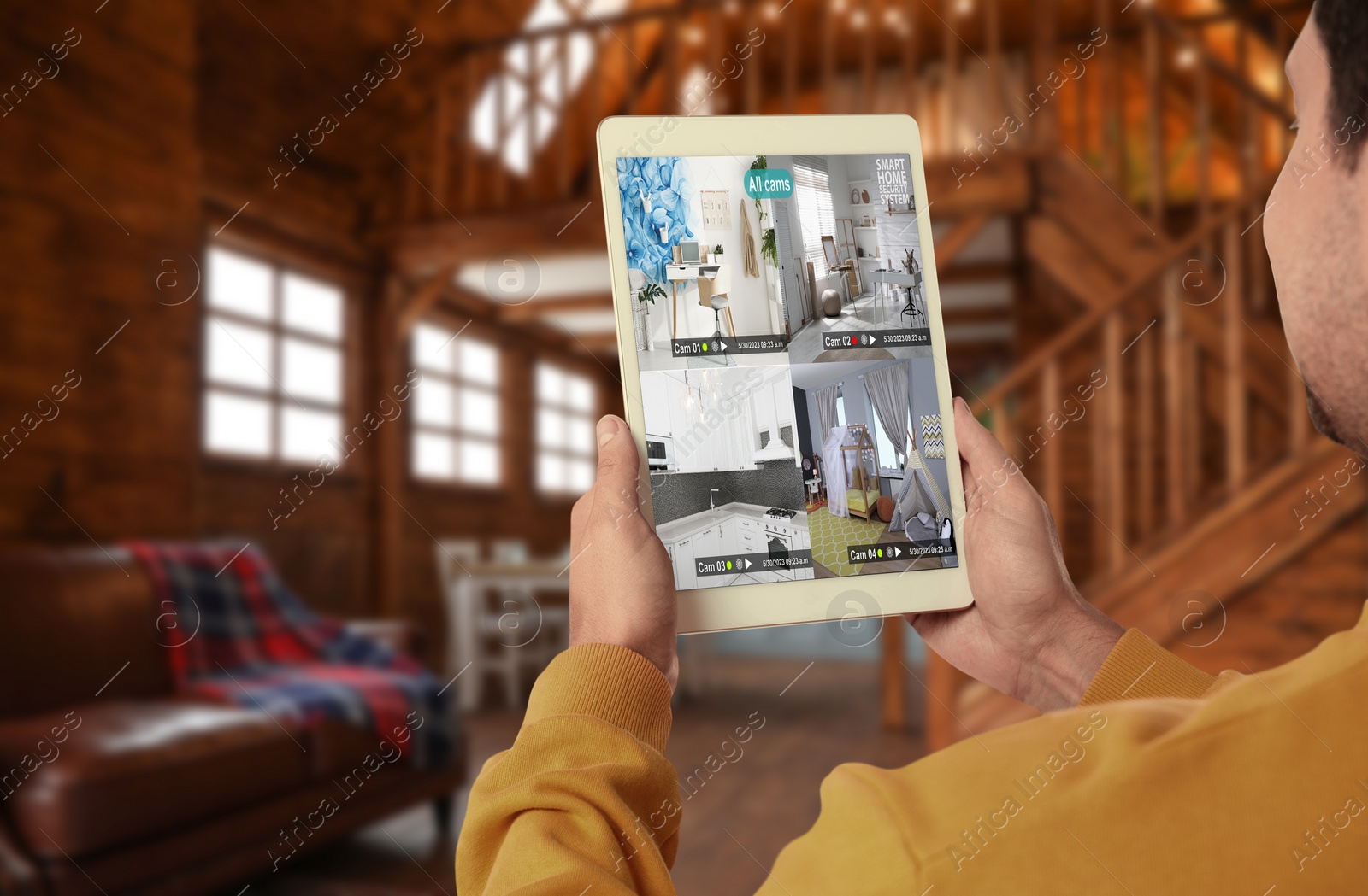 Image of Man using smart home security system on tablet computer indoors, closeup. Device showing different rooms through cameras