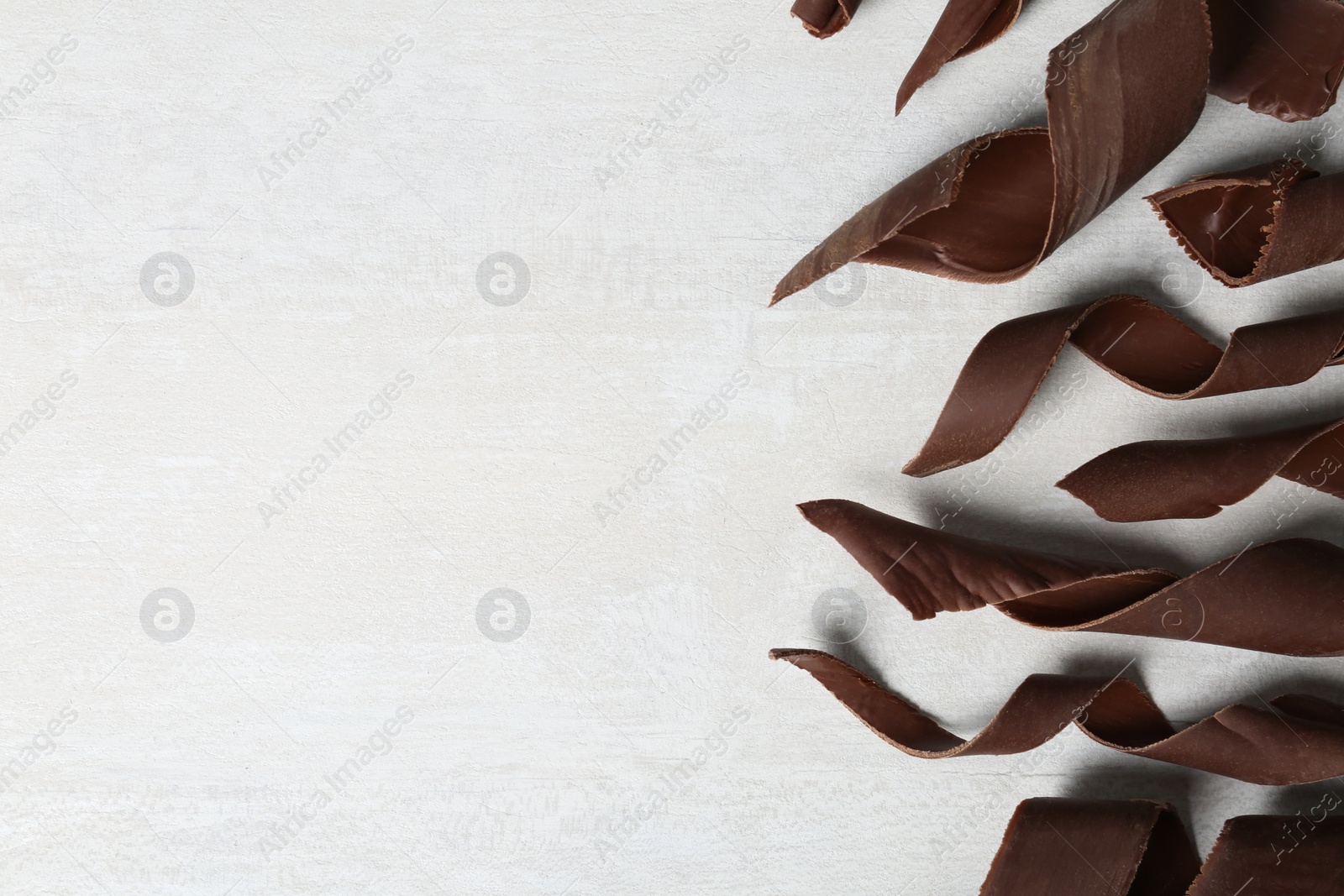 Photo of Chocolate curls on light background, flat lay. Space for text