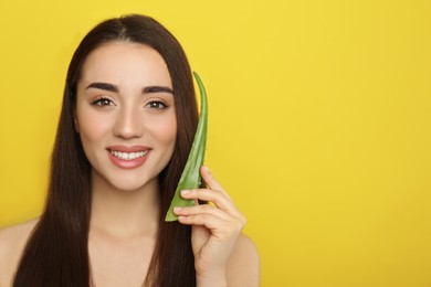 Photo of Young woman with aloe vera leaf on yellow background. Space for text
