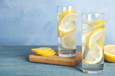 Photo of Soda water with lemon slices on blue wooden table. Space for text