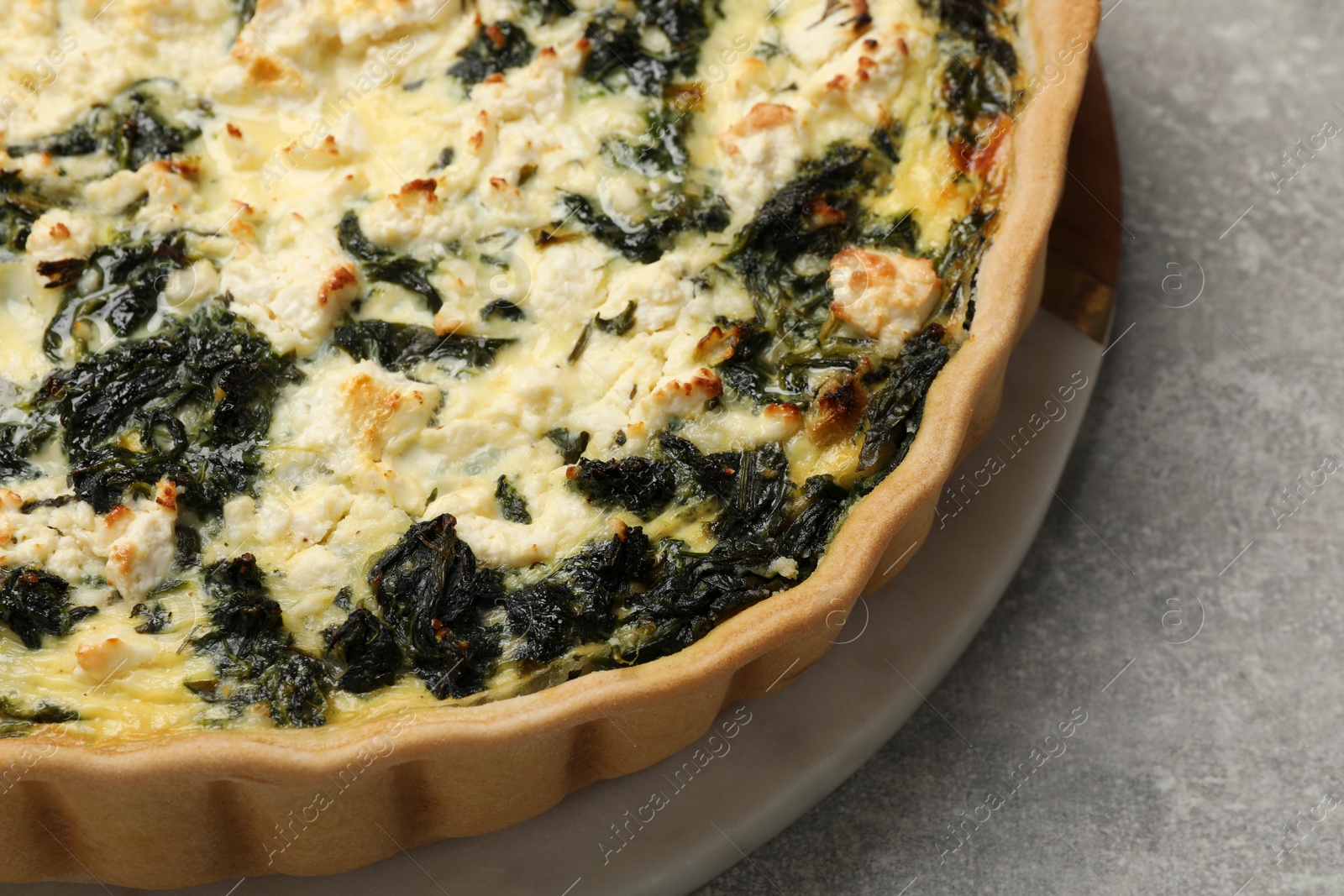 Photo of Delicious homemade spinach quiche on light gray table, closeup