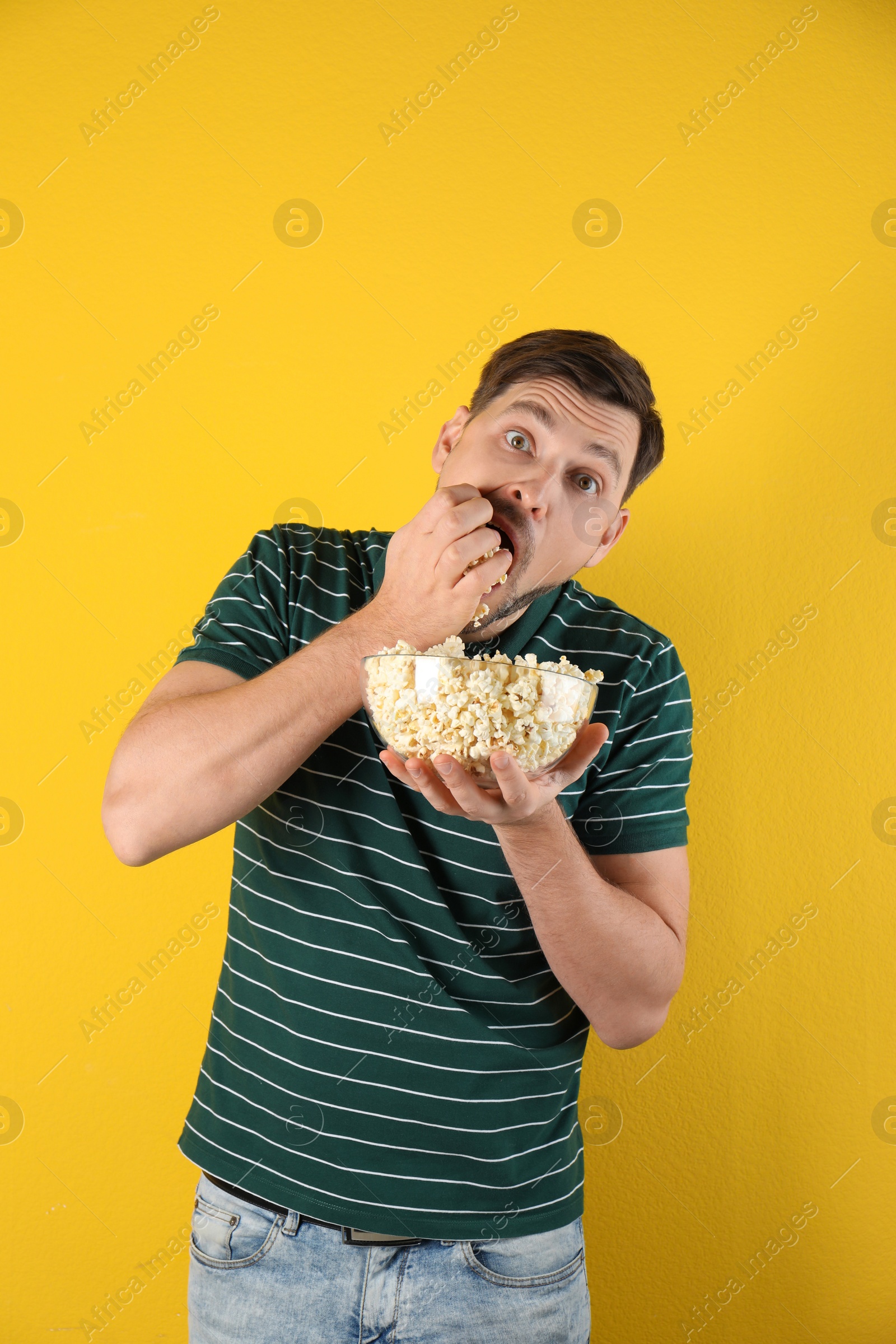 Photo of Man eating tasty popcorn on color background