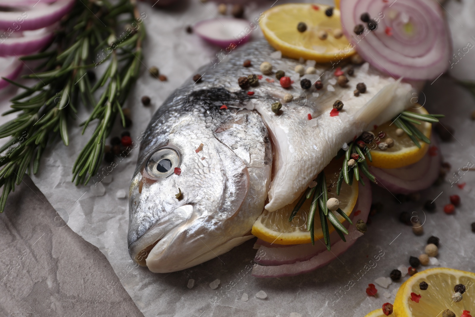 Photo of Fresh raw dorado fish with spices, lemon and onion on table, closeup