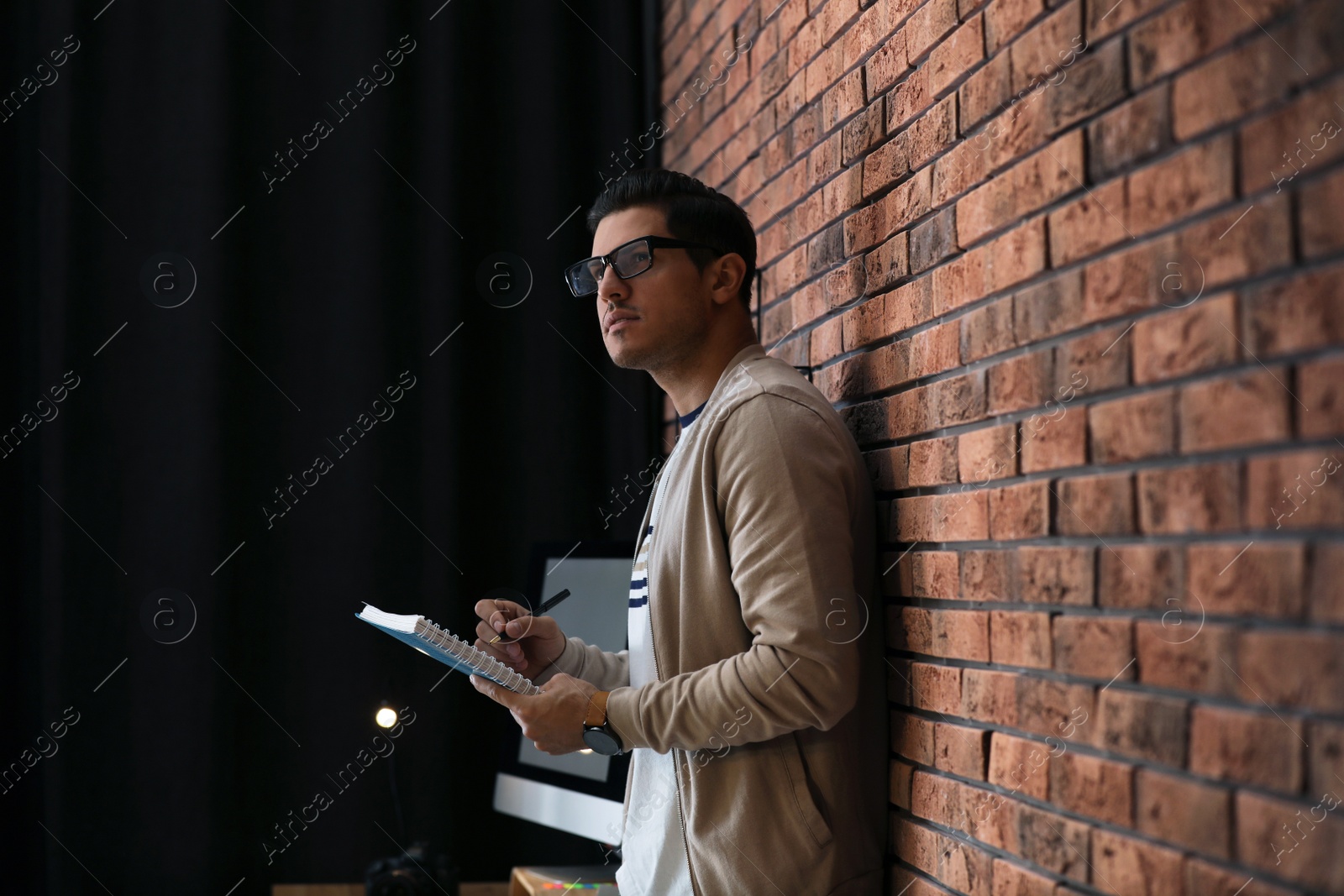 Photo of Journalist with notebook near brick wall in office