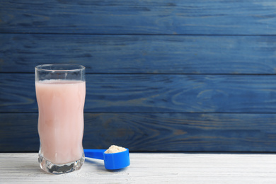 Protein shake and powder on white wooden table, space for text