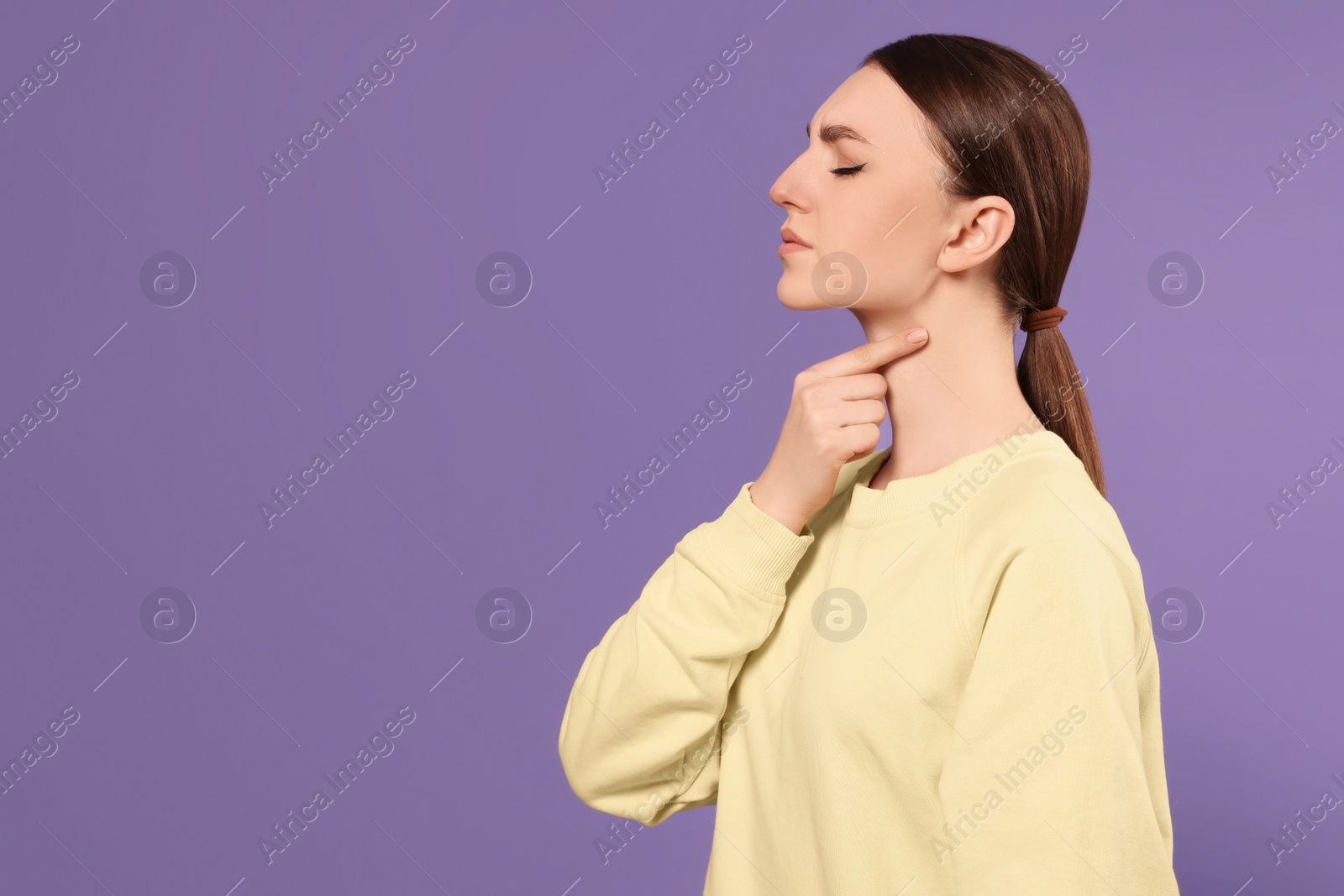 Photo of Young woman with sore throat on violet background. Space for text
