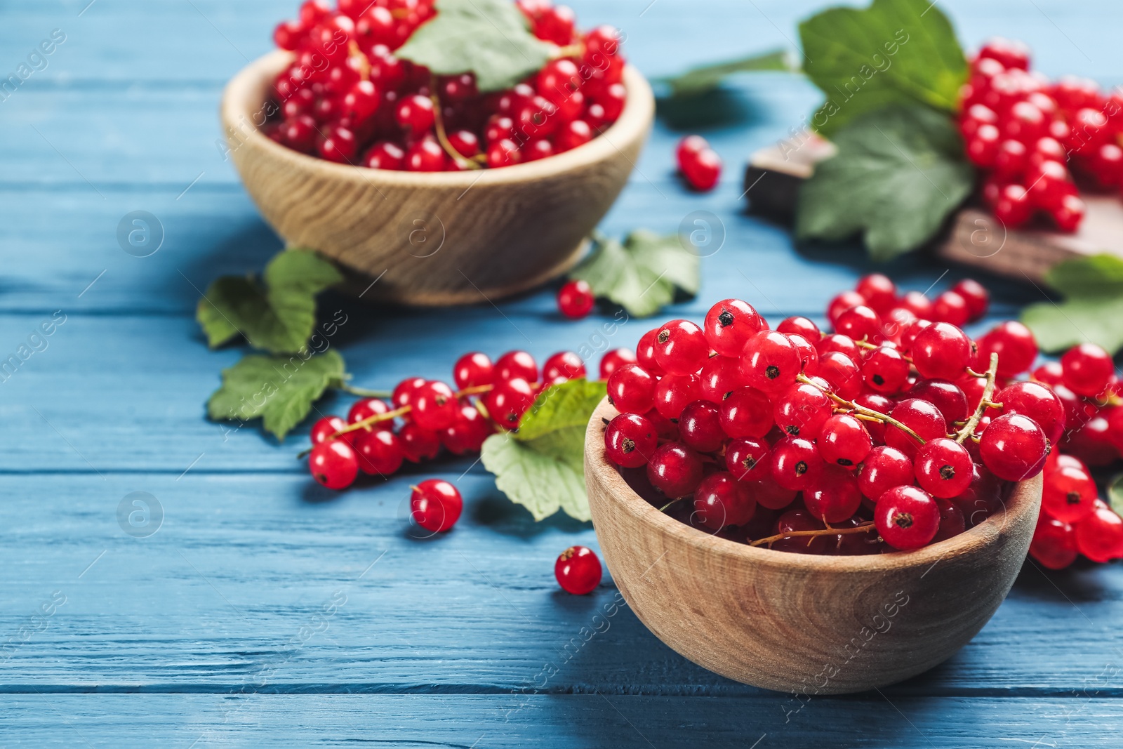 Photo of Delicious red currants on blue wooden table