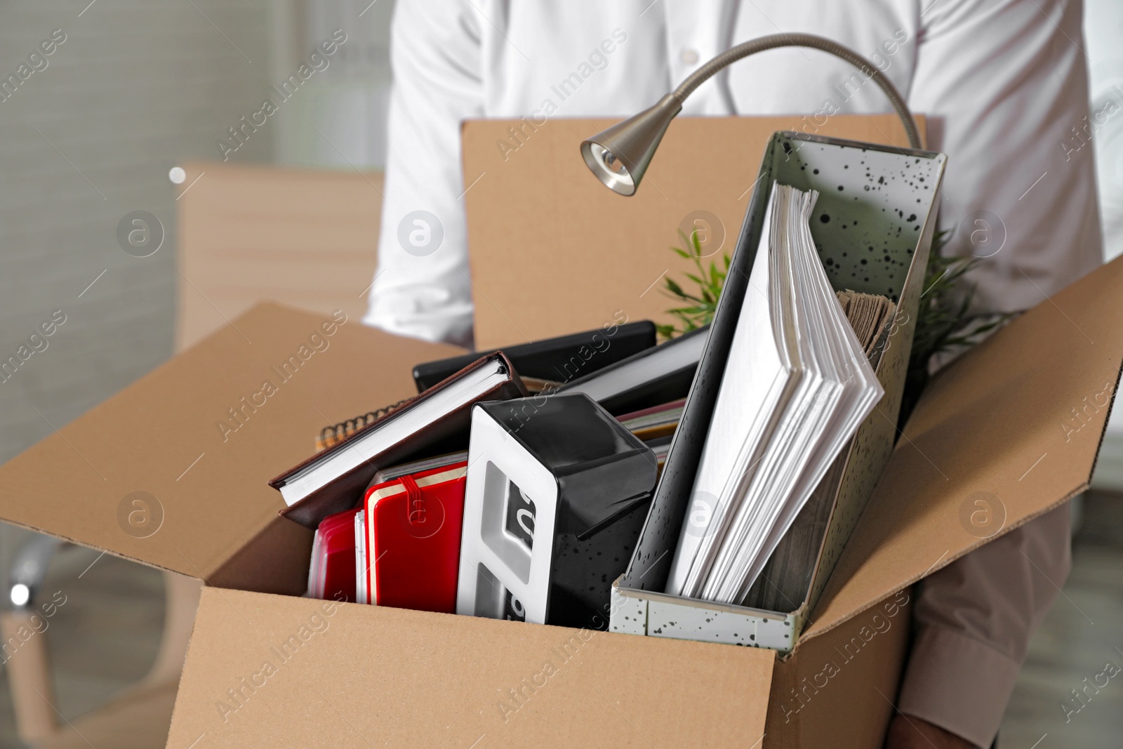 Photo of Young man with box of stuff in office, closeup