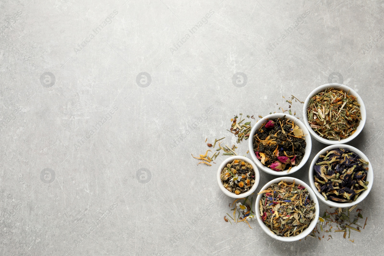 Photo of Flat lay composition with different dry teas on light grey table, space for text