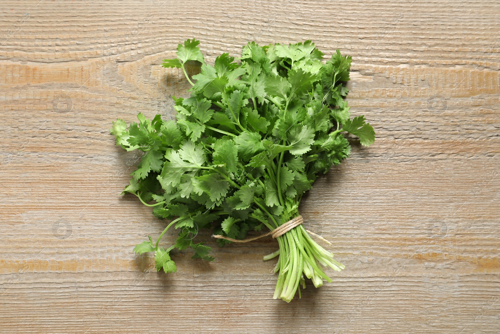 Photo of Bunch of fresh aromatic cilantro on wooden table, top view