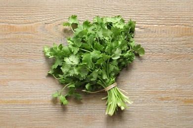 Photo of Bunch of fresh aromatic cilantro on wooden table, top view