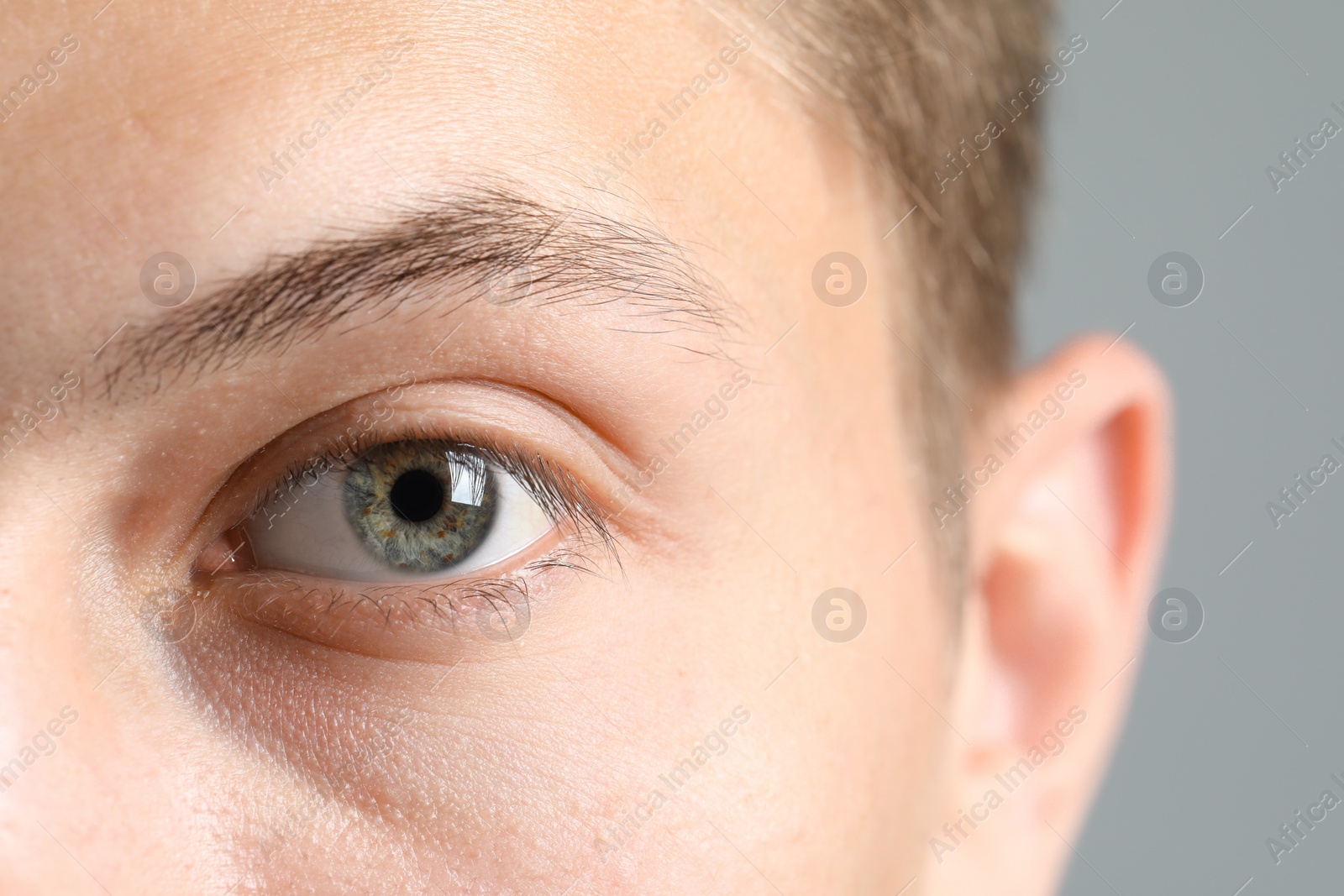 Photo of Perfect vision. Man with beautiful eyes on grey background, closeup