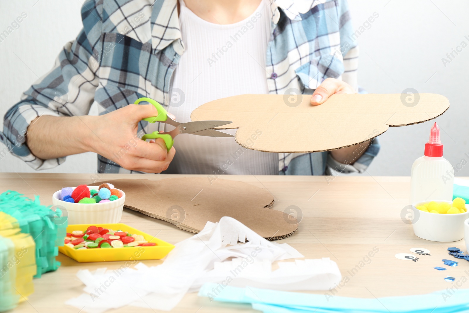 Photo of Woman making cardboard cloud at wooden table, closeup. Pinata diy