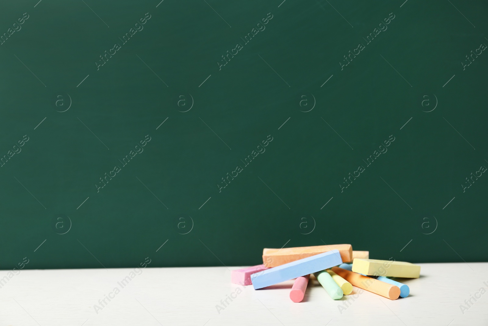 Photo of Pieces of chalk on table near board