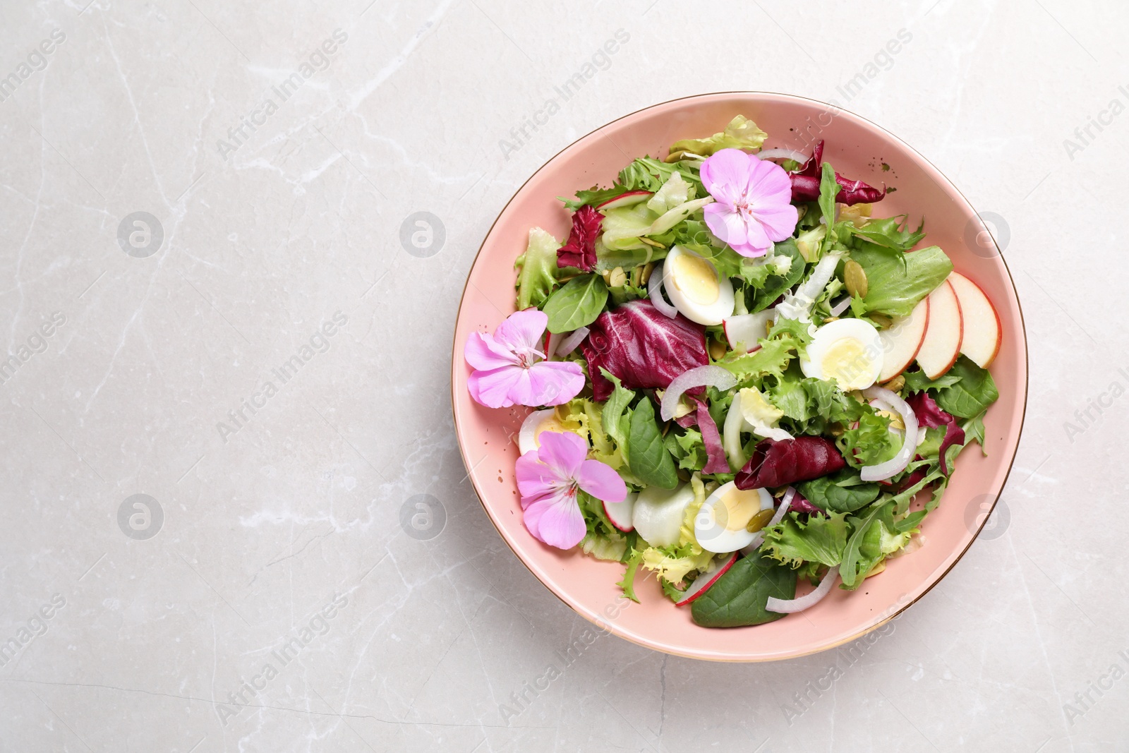 Photo of Fresh spring salad with flowers on grey table, top view. Space for text